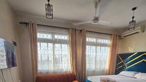 Une chambre d’hôtel avec un lit, un canapé, une petite table ronde et un téléviseur.