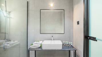 A modern bathroom with a white sink, a glass shower enclosure, and a framed mirror above the sink.