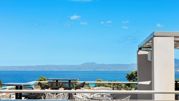 A terrace with outdoor seating, a view of the sea, and distant mountains. - Arya Hotel (Kassandra)