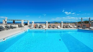 A clear blue pool with lounge chairs and umbrellas, a lifebuoy, and a view of the sea and mountains. - Arya Hotel (Kassandra)