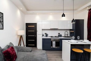 Cozy living space with a kitchenette, sofa, and floor lamp.
