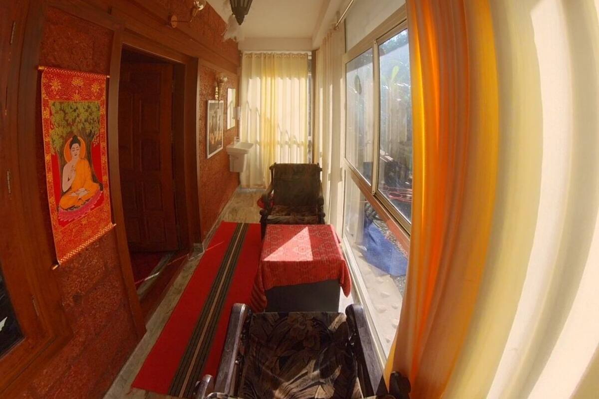 Um corredor com parede de madeira, tapete vermelho, cadeira de madeira e uma janela com cortinas.