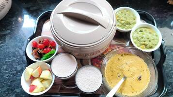 A tray with various food items including bowls of fruit, a bowl of soup, and a bowl of porridge.