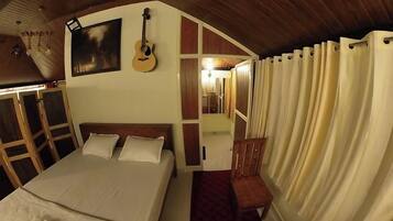A bedroom with a bed, a guitar, a chair, and a mirror.