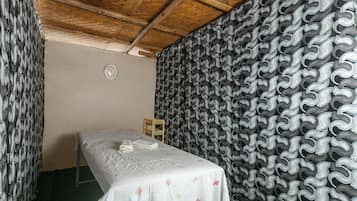 A room with a bed, a wall clock, and a patterned wallpaper.