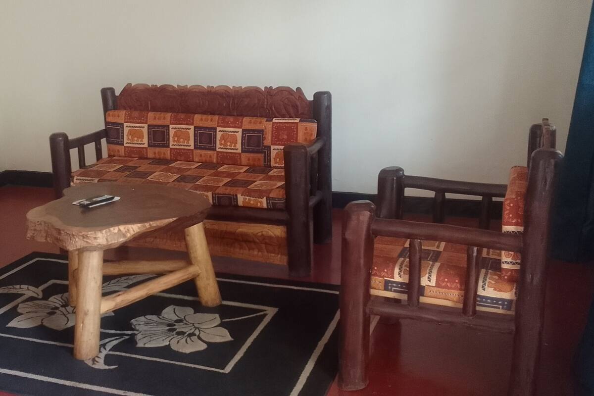 A room with a sofa, two chairs, a small table, and a patterned rug.