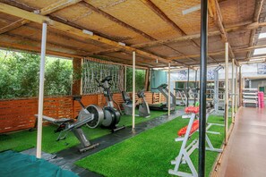 A covered gym with exercise equipment, artificial grass, and a wooden deck. - Dream Jet Suites (Entebbe)