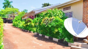 A pathway leading to a building with a satellite dish and lush greenery. - Dream Jet Suites (Entebbe)