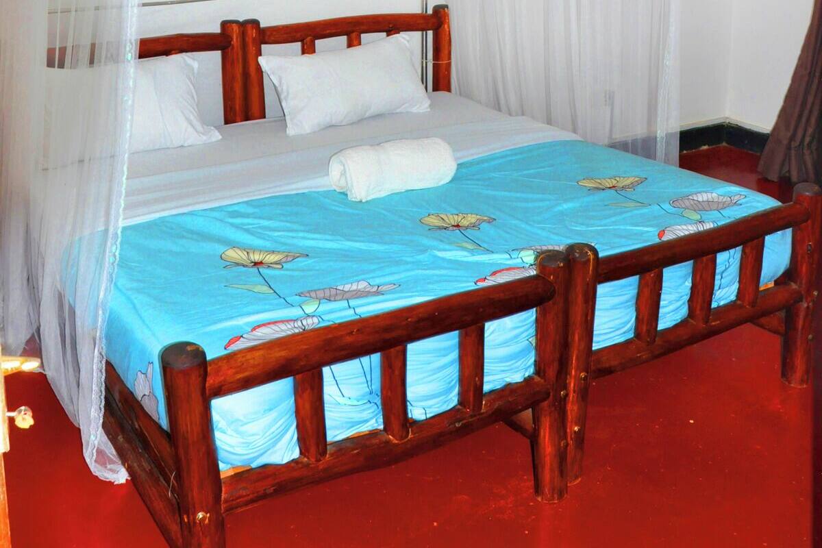 A bed with a blue bedspread and white pillows, a wooden headboard, and a canopy with lace detailing.