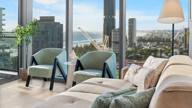 A modern living room with a large window, a sofa, two armchairs, and a floor lamp.