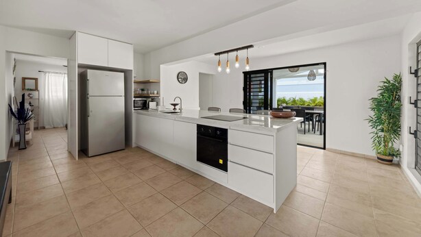 A modern kitchen with white cabinetry, a built-in oven, and a large island with a sink.