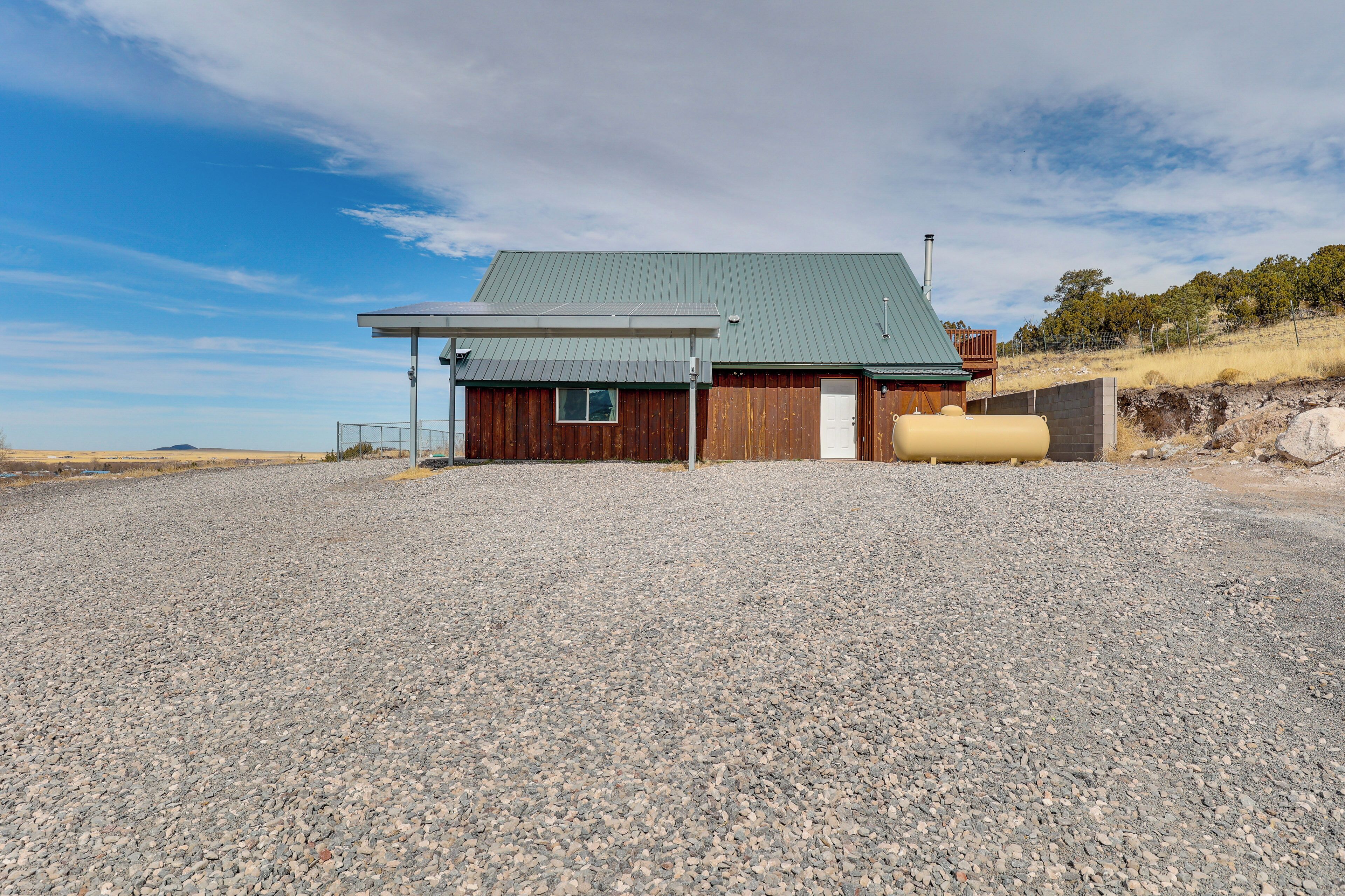 A building with a green roof, wooden walls, and a gravel driveway.
