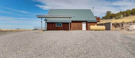 A building with a green roof, wooden walls, and a gravel driveway.