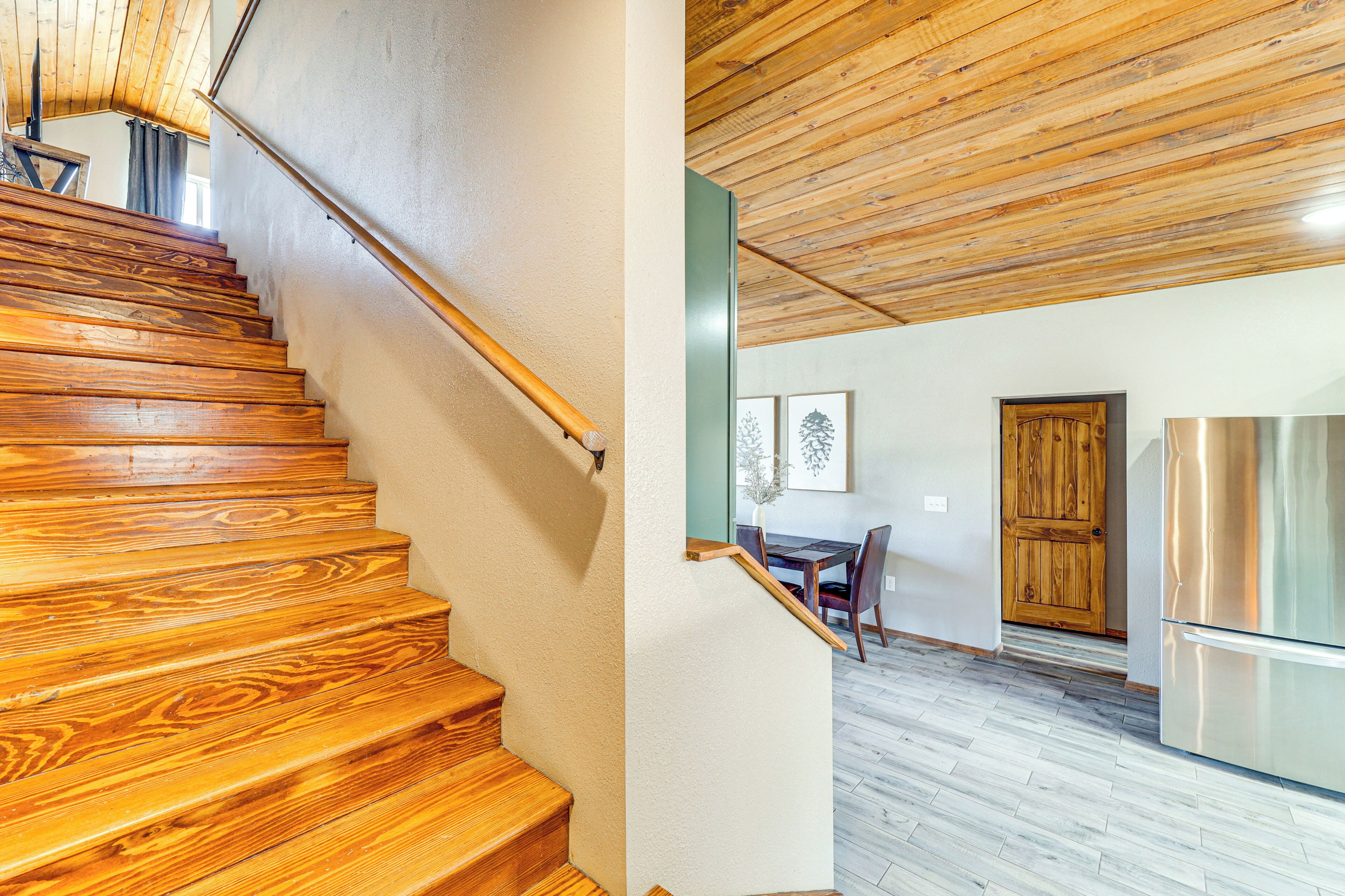 A wooden staircase leading to a room with a dining area and a kitchen.