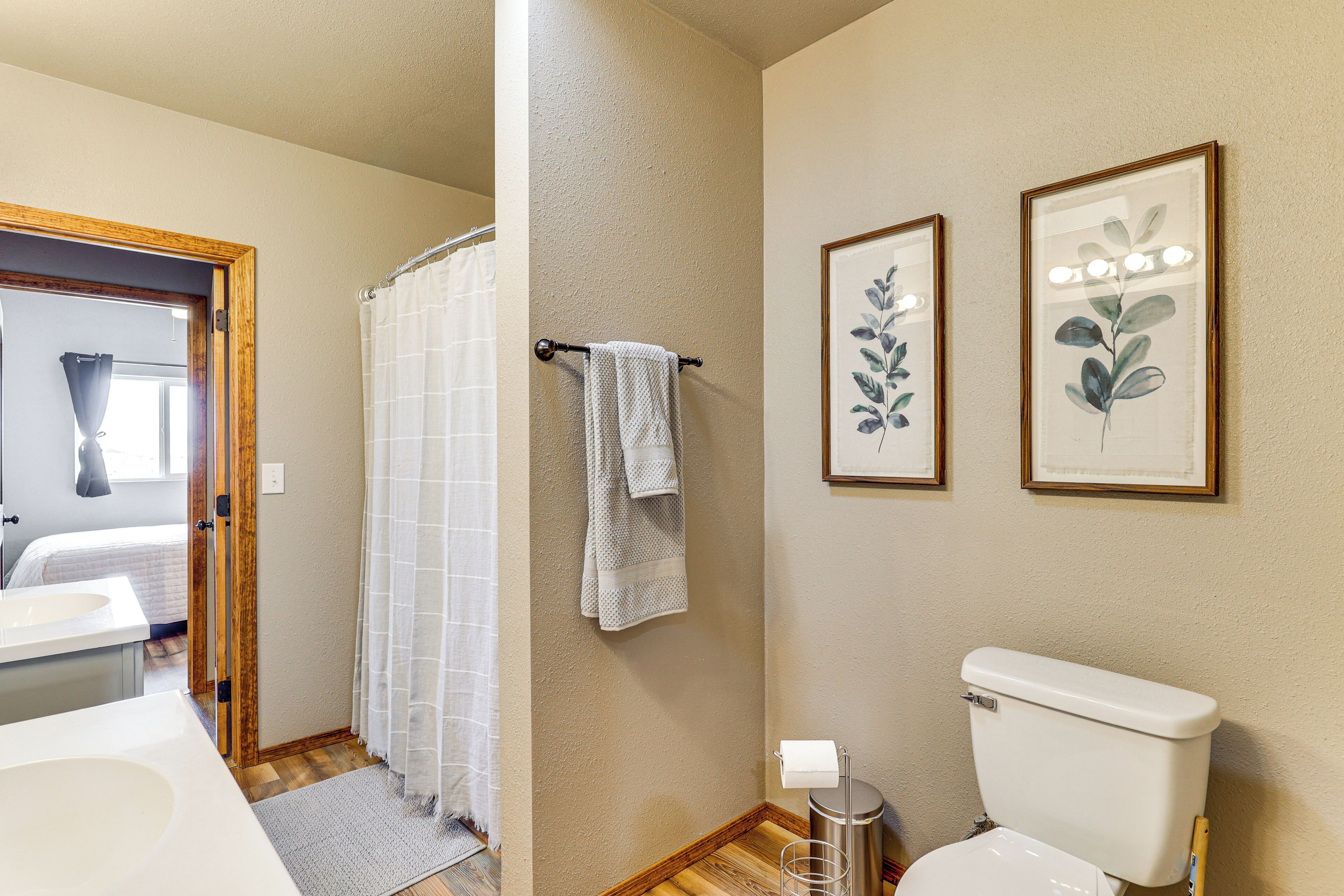 Ein Badezimmer mit Toilette, Duschvorhang und zwei gerahmten Pflanzenmotiven an der Wand.