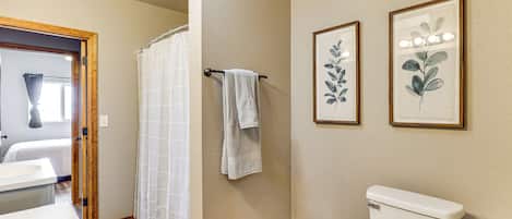 Ein Badezimmer mit Toilette, Duschvorhang und zwei gerahmten Pflanzenmotiven an der Wand.