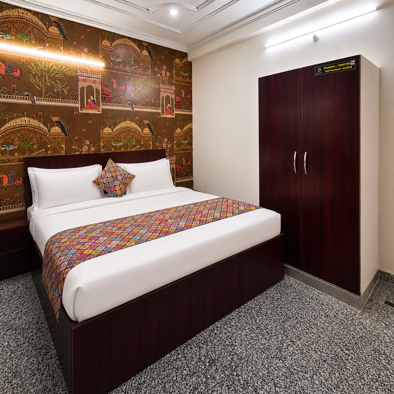 A hotel room with a large bed, a wardrobe, and a wall with traditional artwork.