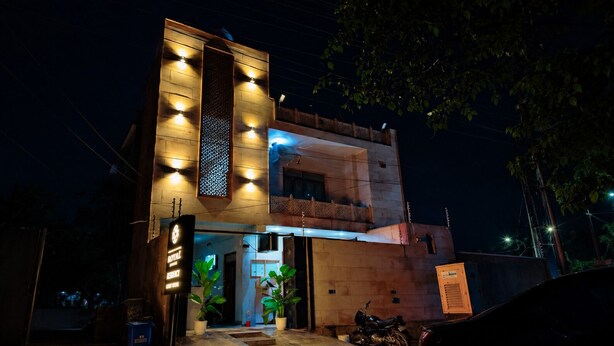 A modern building with a well-lit entrance, a visible signboard, and a motorcycle parked outside. - The Manthan Stays (Vrindavan)