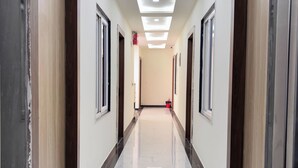 A long, narrow hallway with a polished marble floor and recessed ceiling lighting. - The Manthan Stays (Vrindavan)