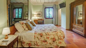A bedroom with a bed, a nightstand, a dresser, a mirror, and a window. - Albergo Villa San Michele  (Greve in Chianti)