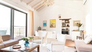 Sala de estar ampla com uma grande janela, móveis brancos e uma varanda.