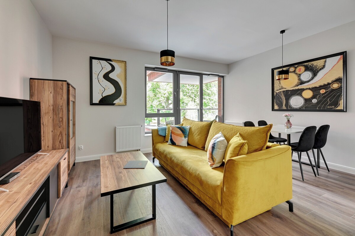 Una sala de estar moderna con un sofá amarillo, una mesa de centro de madera y sillas negras.