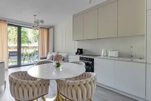 A modern kitchen with white cabinets, a round dining table, and two tufted chairs.