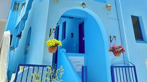 Een blauw gebouw met een receptie, een trap en bloembakken met bloemen.