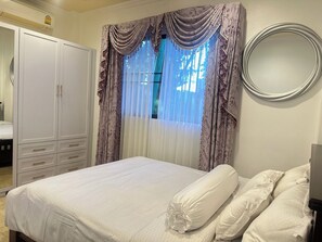 Comfortable retreat with a neatly made bed, spacious wardrobe, and stylish mirror.
