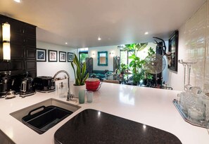 Una cucina moderna con lavandino, macchina da caffè e tostapane. Si vedono piante in vaso e un'area da pranzo sullo sfondo.