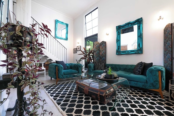 Un salon comprenant un ensemble de canapés, une table basse, un tapis à motifs et un escalier.