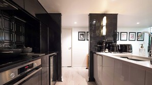 A modern kitchen with stainless steel appliances, a white countertop, and black cabinetry.