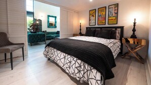 A bedroom with a bed, a chair, a nightstand, a lamp, and a poster on the wall.