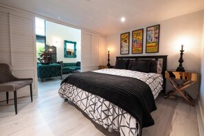 A bedroom with a bed, a chair, a nightstand, a lamp, and a poster on the wall.