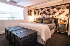 Ein Schlafzimmer mit Bett, Nachttischen, einem Koffer und einer Wand mit kreisförmigen Mustern.