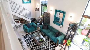 A spacious living area with a staircase, teal sofas, a coffee table, and a large mirror.