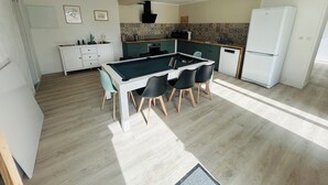 Una cocina moderna con mesa de billar, armarios blancos y refrigerador.