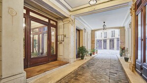 A hallway with a tiled floor, wooden doors, and potted plants. - Luxurious AC apartment Saint Honoré (Paris)
