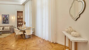 A modern living room with a herringbone wood floor, a dining area with a white table and chairs, a sofa, and a large mirror on the wall. - Luxurious AC apartment Saint Honoré (Paris)
