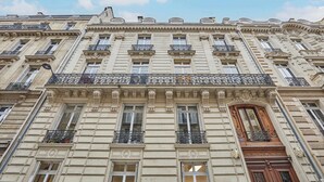 A multi-story building with ornate architectural details, including decorative balconies and a prominent wooden door. - Luxurious AC apartment Saint Honoré (Paris)