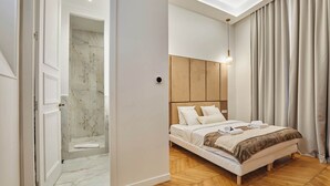 A modern bedroom with a large bed, a wooden headboard, and a walk-in closet. - Luxurious AC apartment Saint Honoré (Paris)