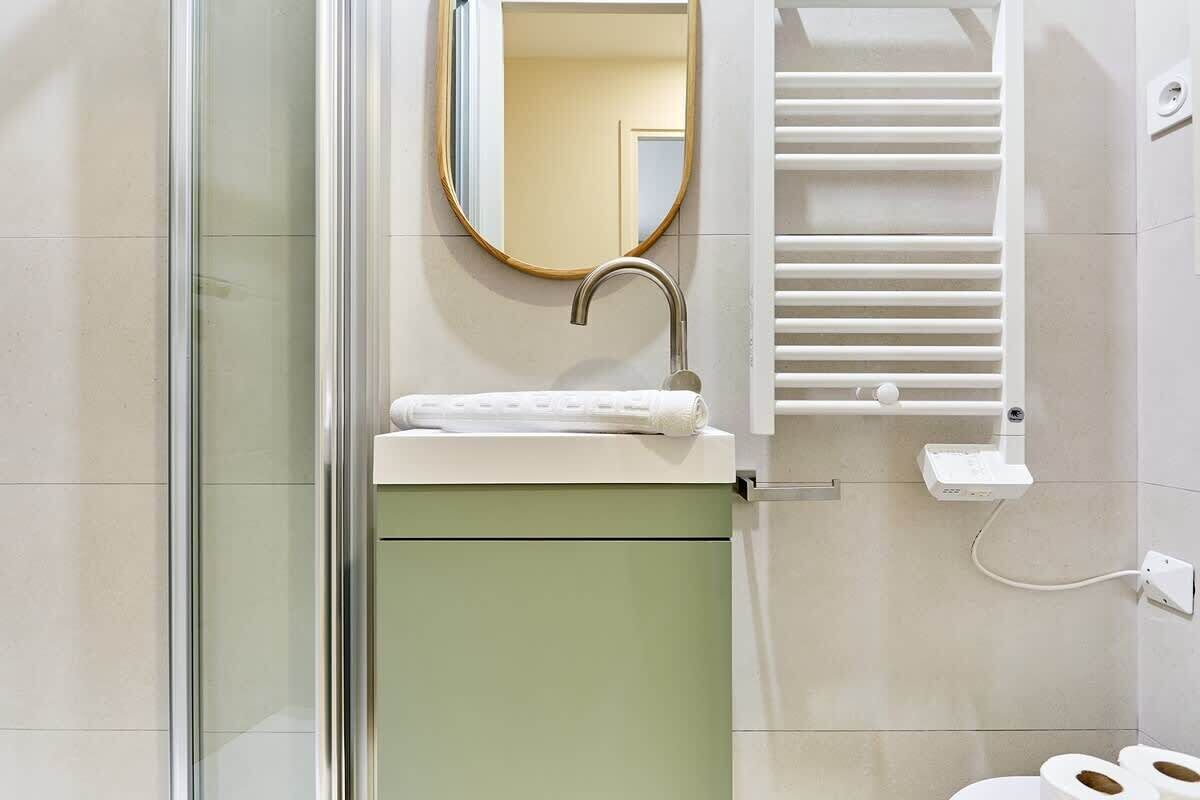 A bathroom with a glass shower enclosure, a sink with a towel, a mirror, and a toilet.