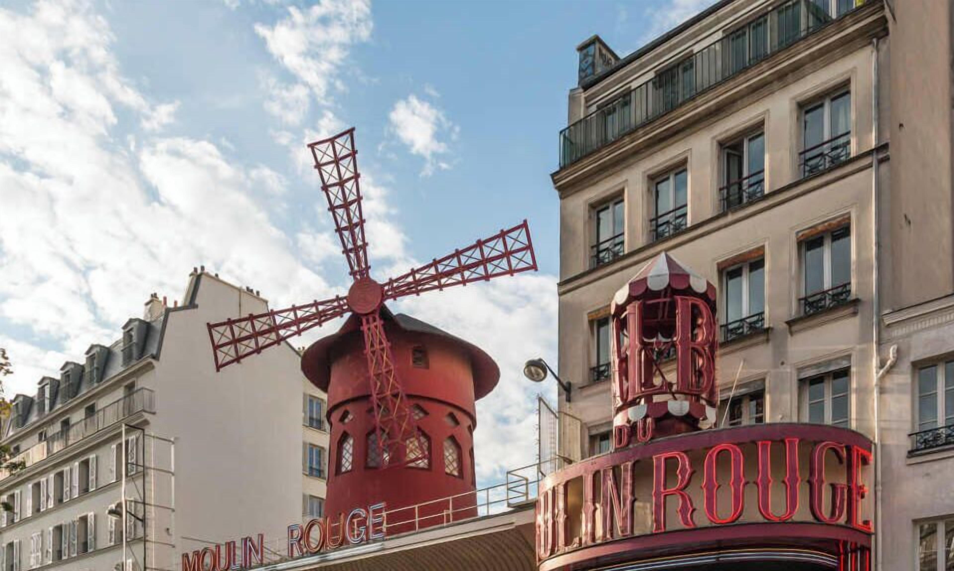 A building with a windmill structure and a sign that reads 'Moulin Rouge.'