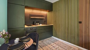 A modern kitchen with dark green cabinetry, a built-in oven, and a coffee machine. - Superb Suite in Neuilly Porte Maillot (Neuilly-sur-Seine)