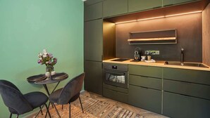 A compact kitchen with a built-in oven, a sink, and a wooden countertop. There is a dining area with a table and chairs, and a vase with flowers on the wall. - Superb Suite in Neuilly Porte Maillot (Neuilly-sur-Seine)