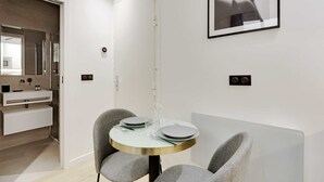 A modern dining area with a round table, two grey chairs, and a minimalist design. - Modern Studio with AC in the heart of Paris (Paris)
