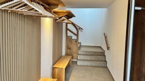 Un escalier en bois avec un banc, un mur en bois avec des lattes verticales et une main courante en bois.