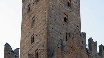 Ein historischer Wehrturm aus Stein mit zahlreichen Fenstern und Zinnen, Teil einer größeren befestigten Anlage.