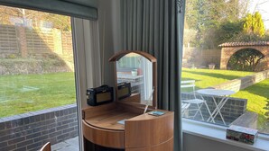 Habitación pequeña con un escritorio de madera, una silla con un cojín con la bandera del Reino Unido, una radio y un espejo.