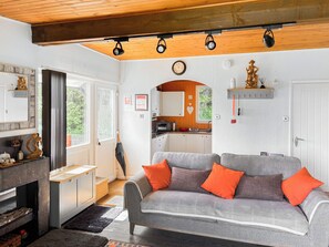 A cozy living area with a grey sofa, wooden ceiling, and a kitchen in the background. - 1 bedroom accommodation in Bideford (Bideford)